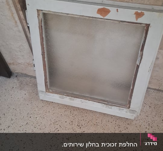 חלון זכוכית ישן עם מסגרת פגומה